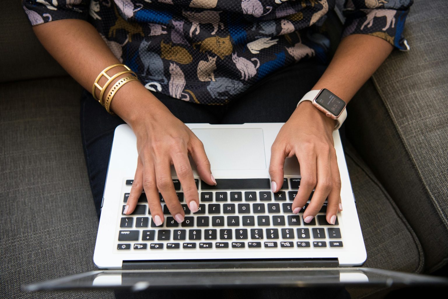 A Black woman's hands typing articles on a laptop